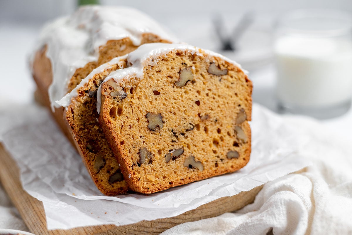 Sweet potato bread loaf on a serving board with two pieces sliced.