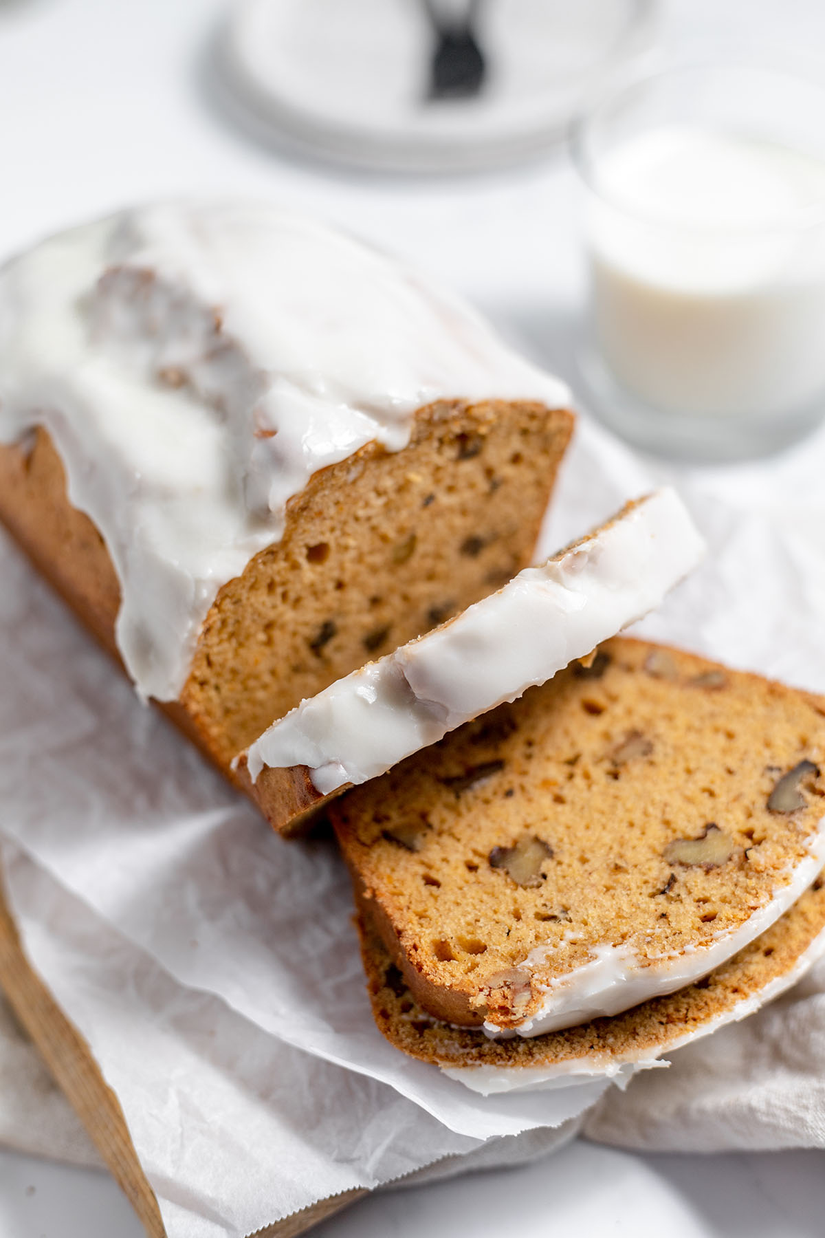 Sweet potato bread topped with icing and two slices cut on a wooden serving board.
