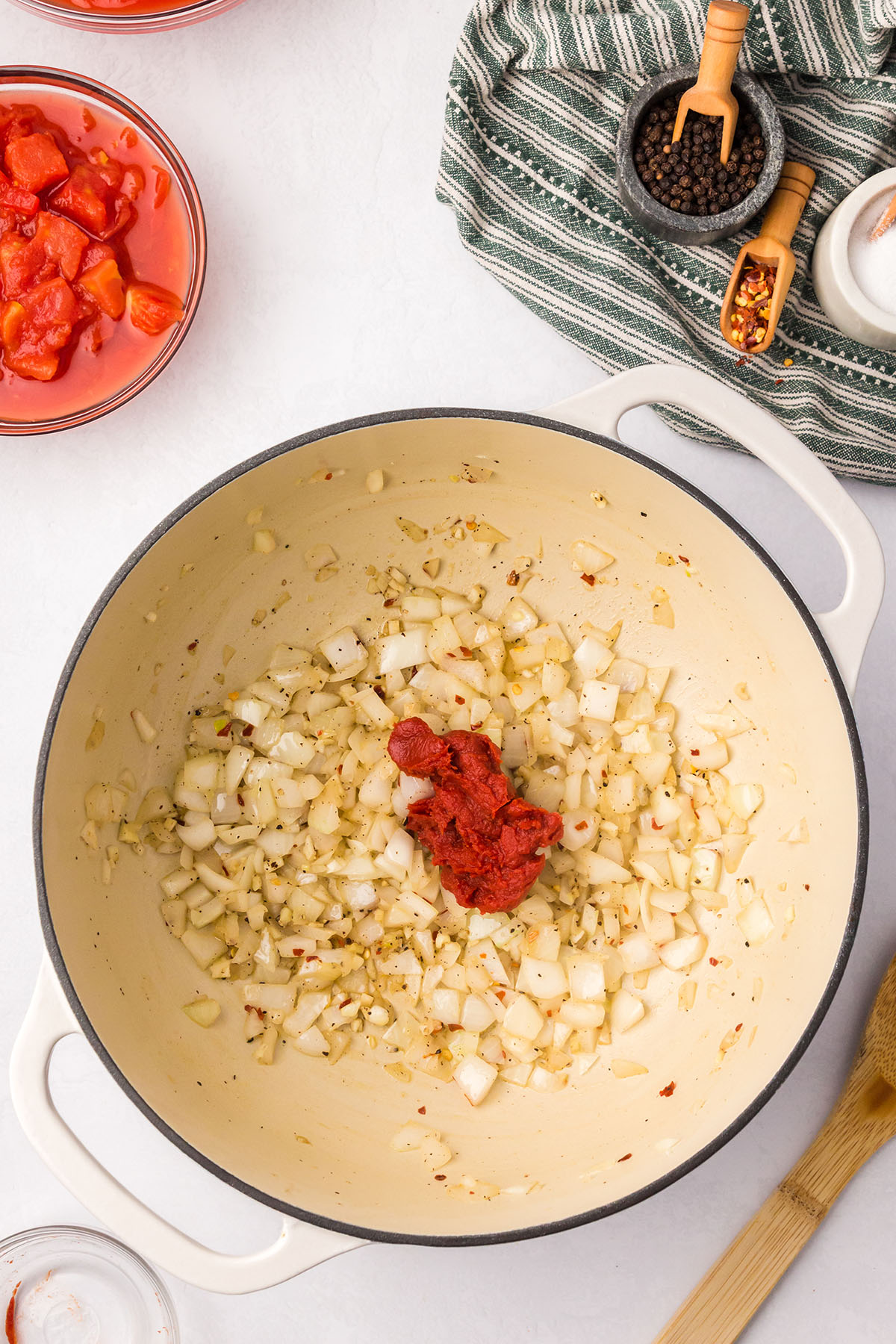 Tomato paste is added to the sauteed onions, garlic, and seasonings in the large pot.
