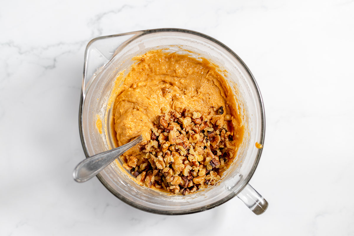 Walnuts are added to the sweet potato batter in the mixing bowl.