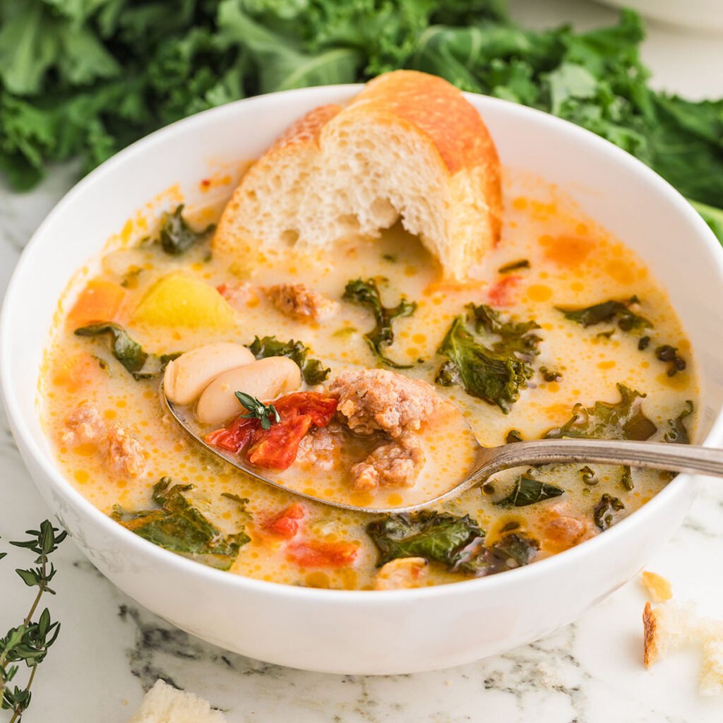 Sausage and Kale Soup served in a white bowl with crusty bread.