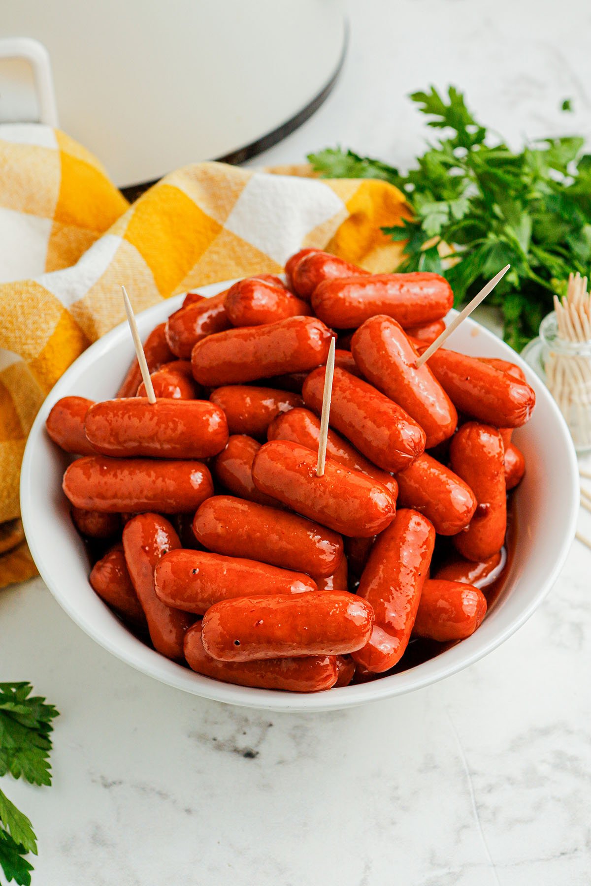 Honey BBQ Little Smokies in a white bowl, with toothpicks inserted in a few of the Little Smokies.