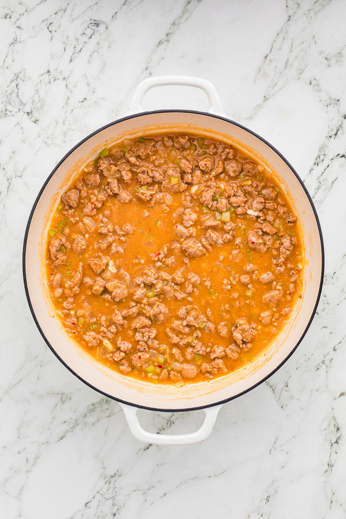 Chicken broth is added to the sausage mixture in the skillet.