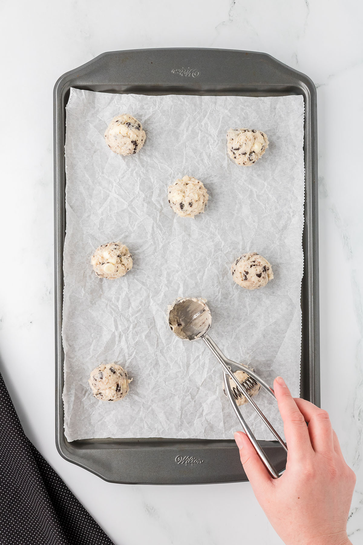 Cookie dough balls placed on a parchment paper lined baking sheet.