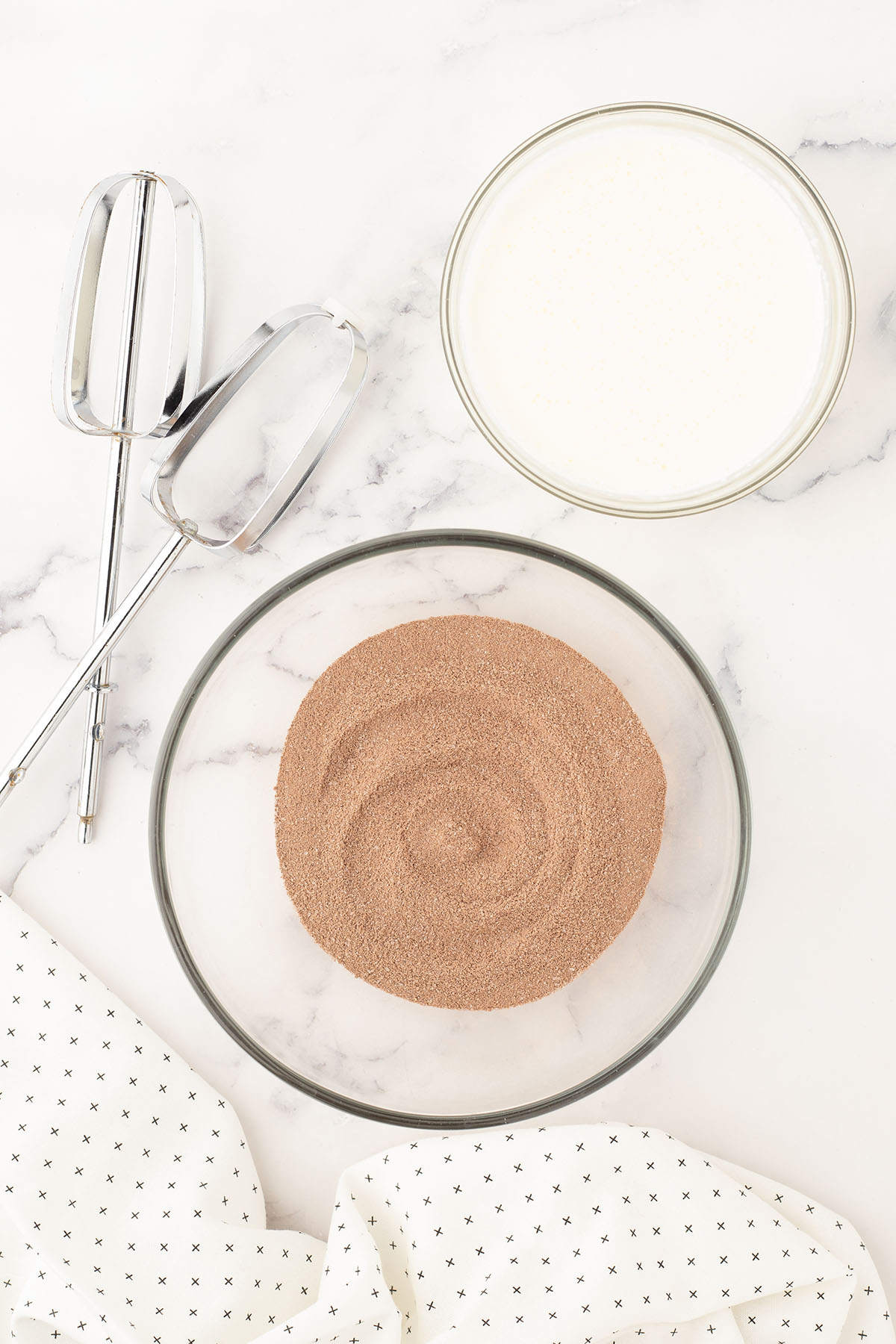 Hot chocolate mix added to a glass mixing bowl.
