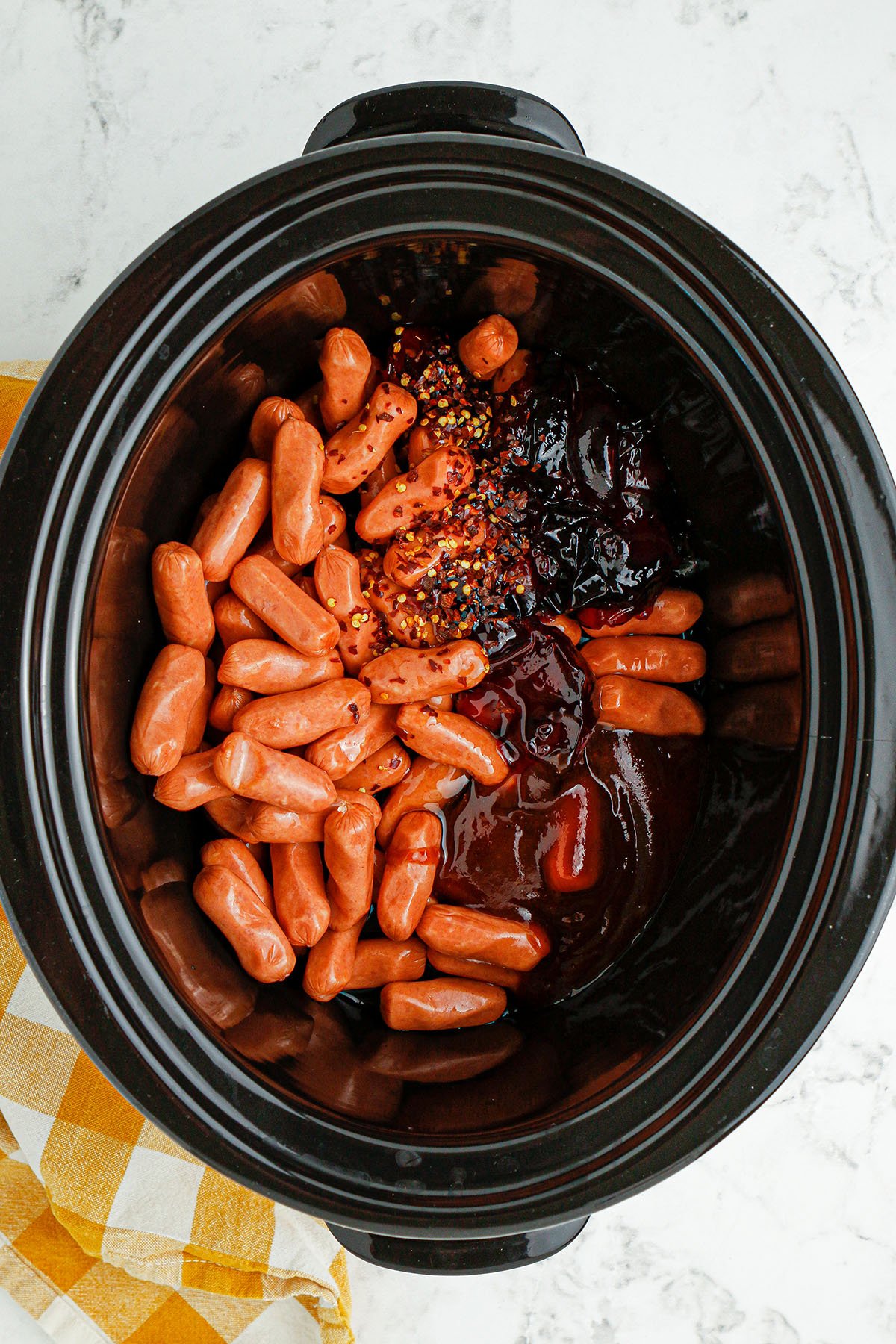 Little smoked sausages, grape jelly, honey, and BBQ sauce in the bottom of the slow cooker.
