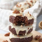 Three Caramel Pecan Brownie Donuts stacked on a wooden serving board.