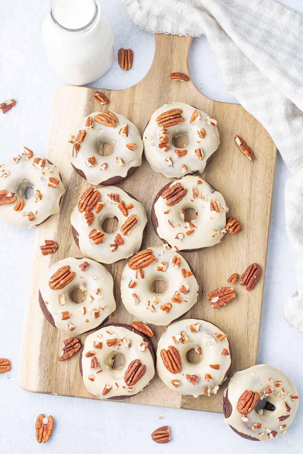 Caramel Pecan Chocolate Donuts on a wooden serving board.