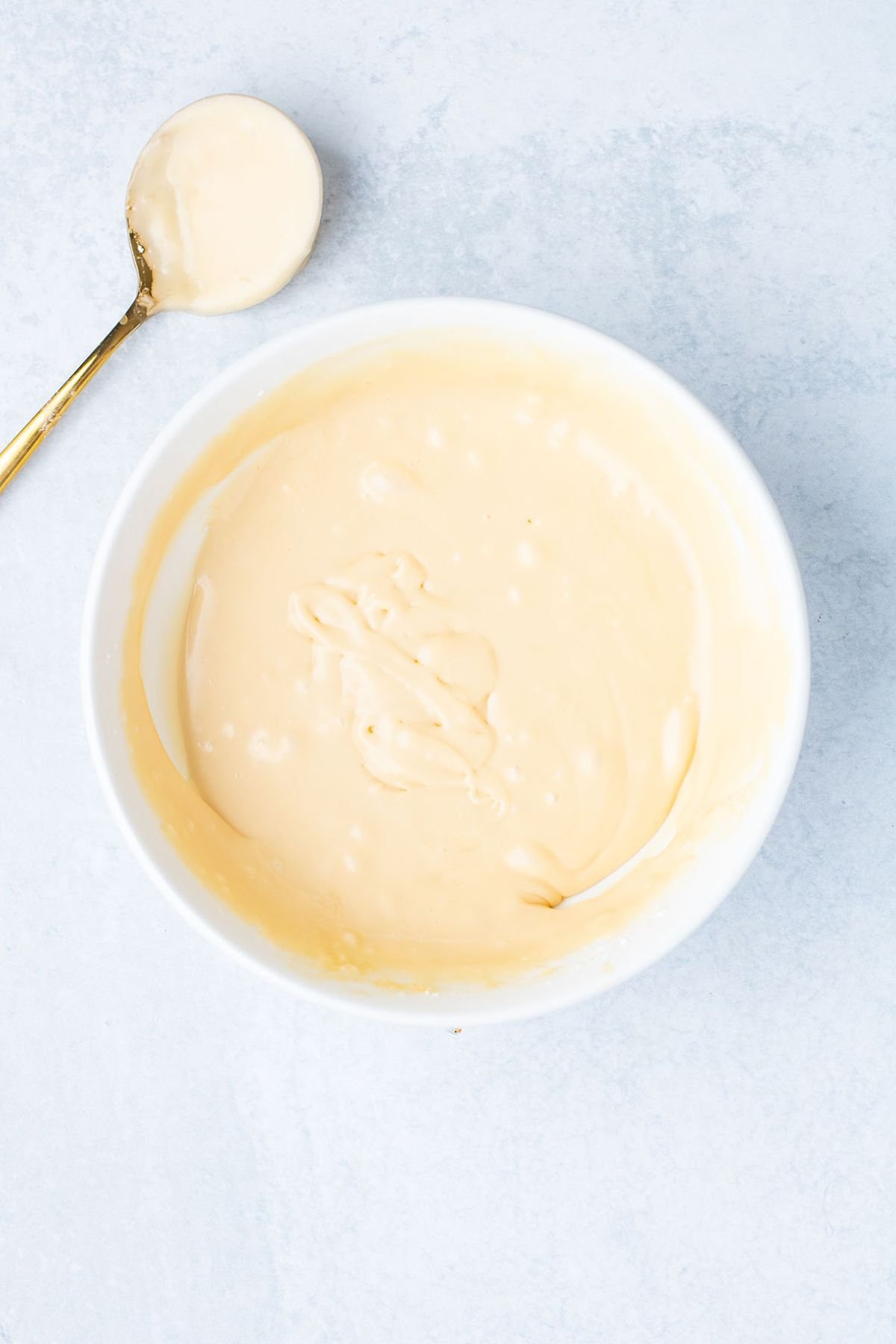 Caramel icing in a white bowl.