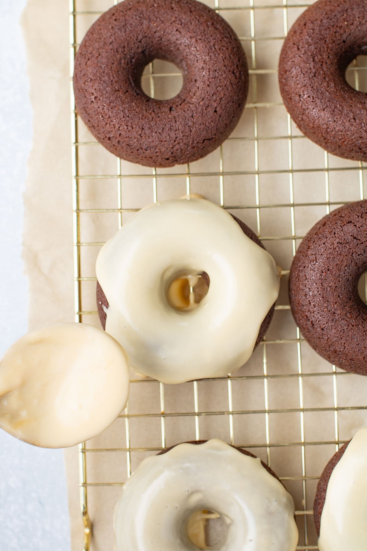 Caramel icing topping added over the donuts on a cooling rack.