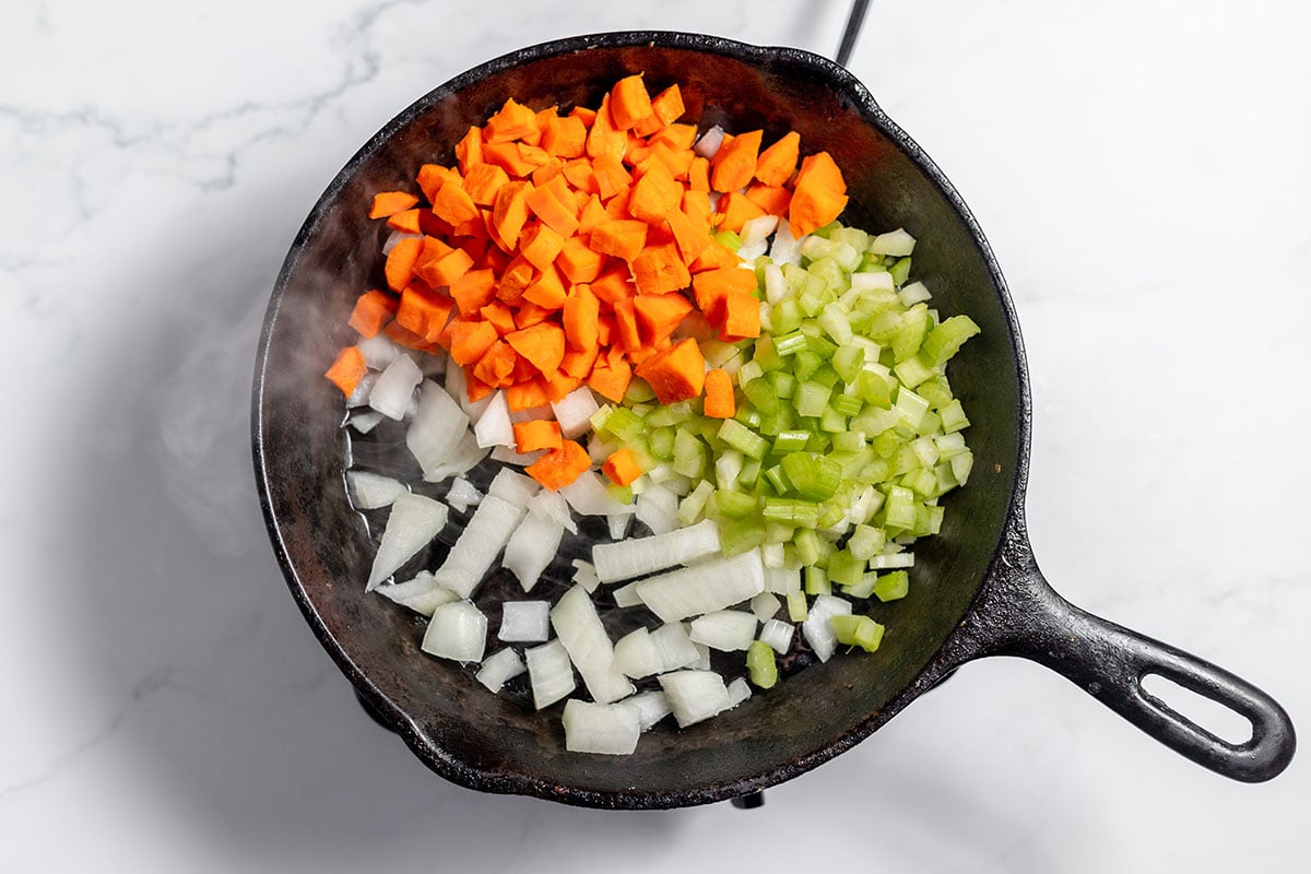 Diced celery, onion, and carrots in a cast iron skillet.
