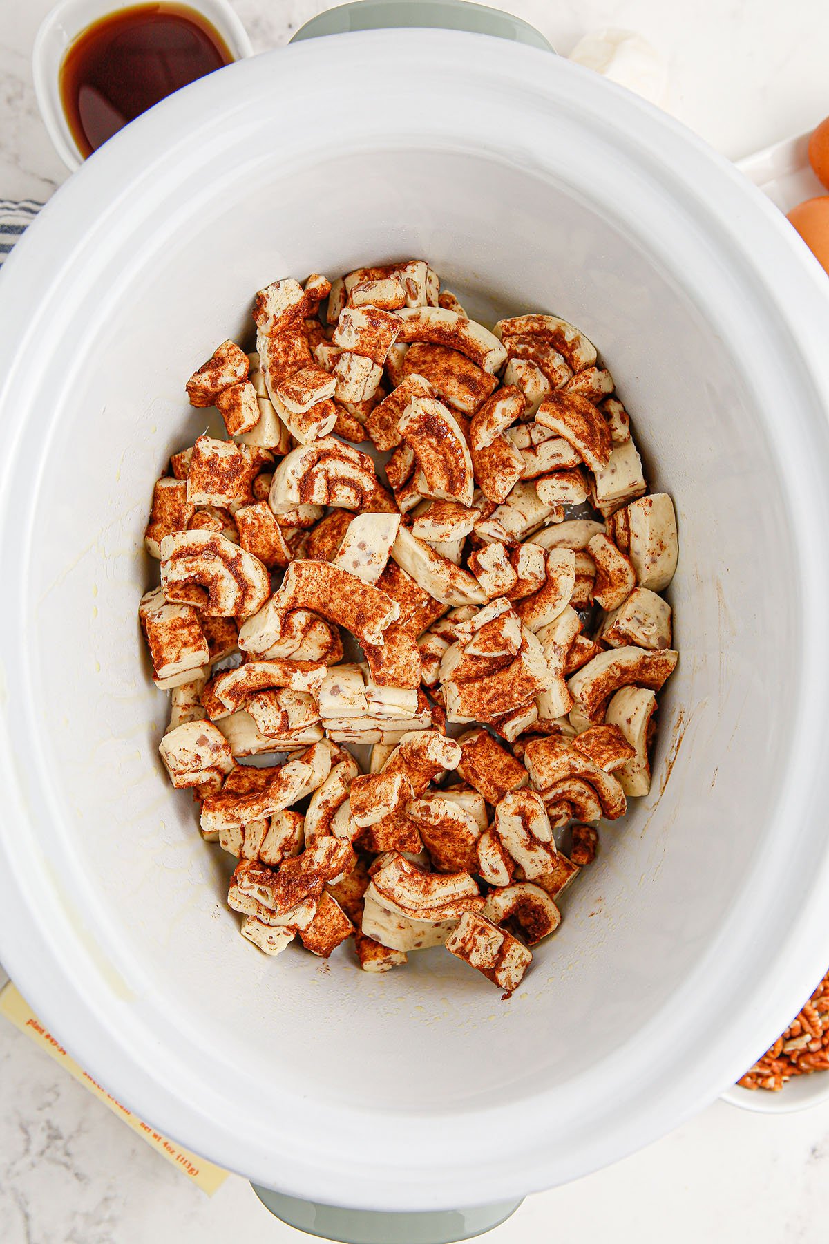 Cinnamon roll pieces placed in the bottom of a slow cooker.