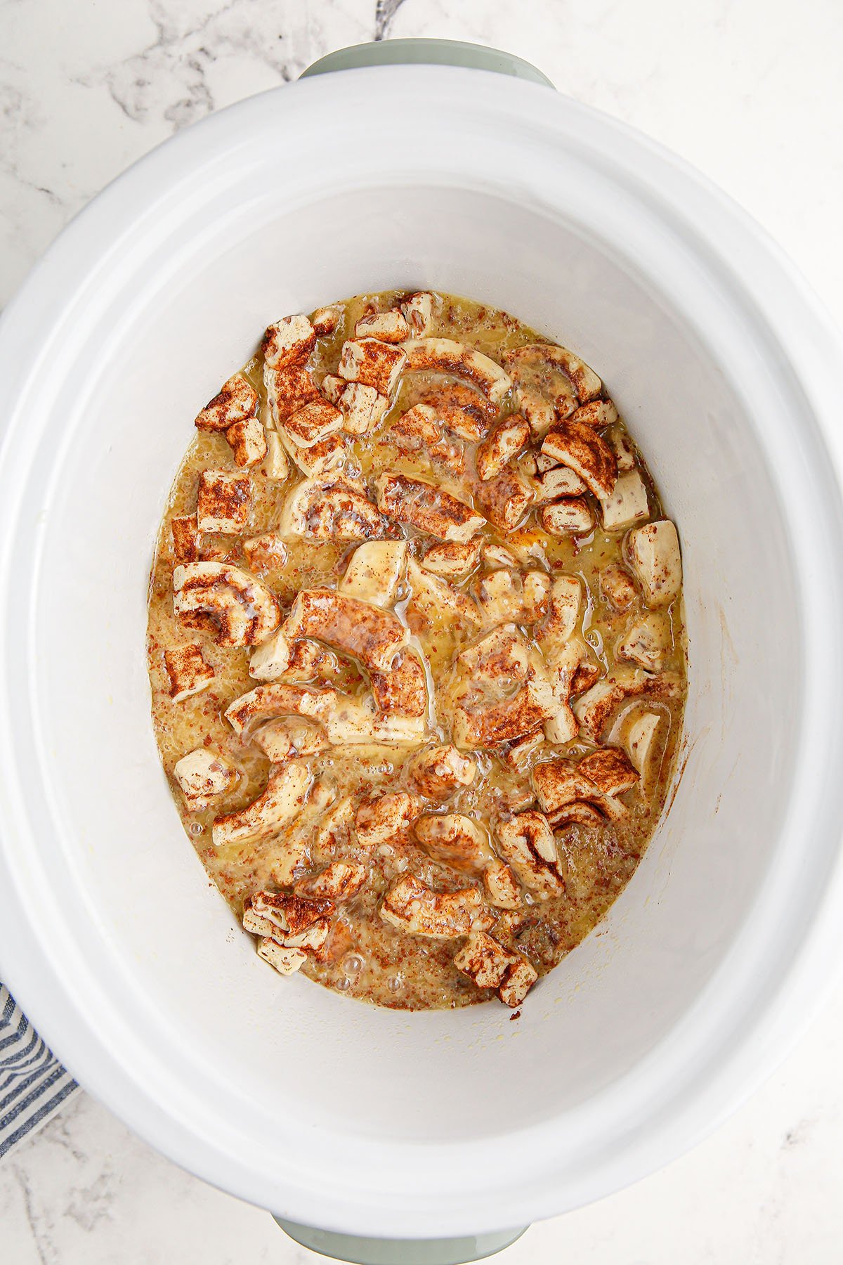 Cinnamon roll pieces, melted butter, eggs, heavy cream, maple syrup, vanilla extract, and cinnamon in the slow cooker.