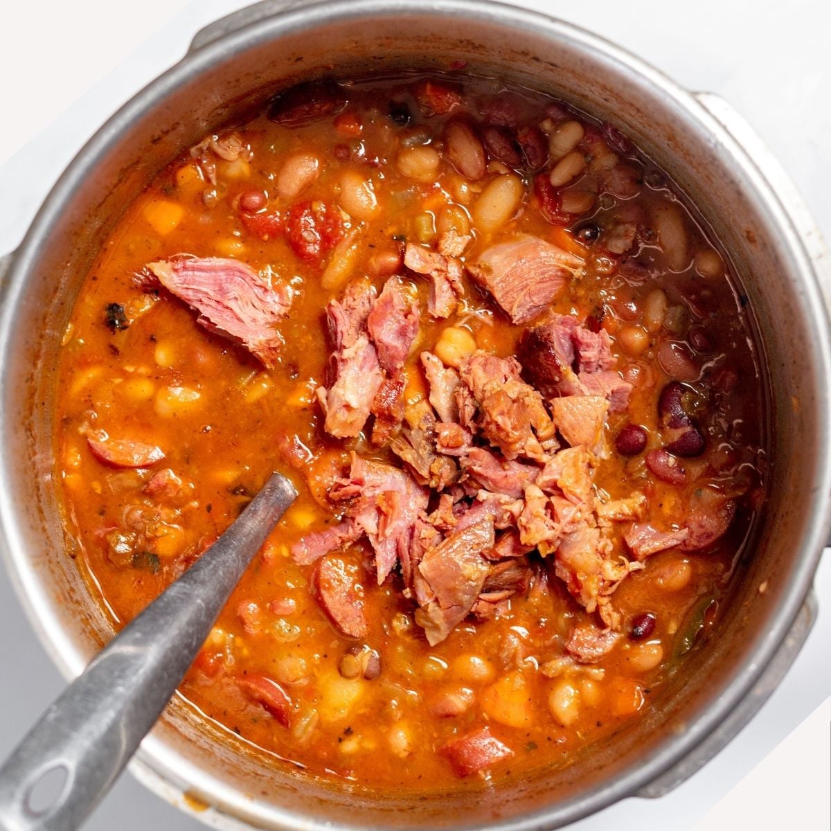 Ham, beans, sausage, vegetables, chicken broth, and seasoning in a large pot.