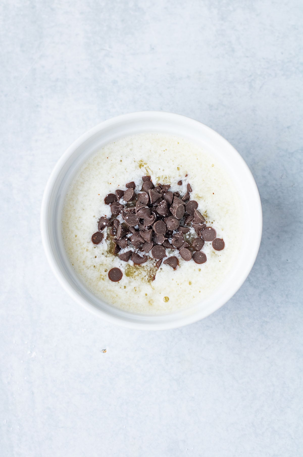 Melted butter and chocolate chips in a white bowl.