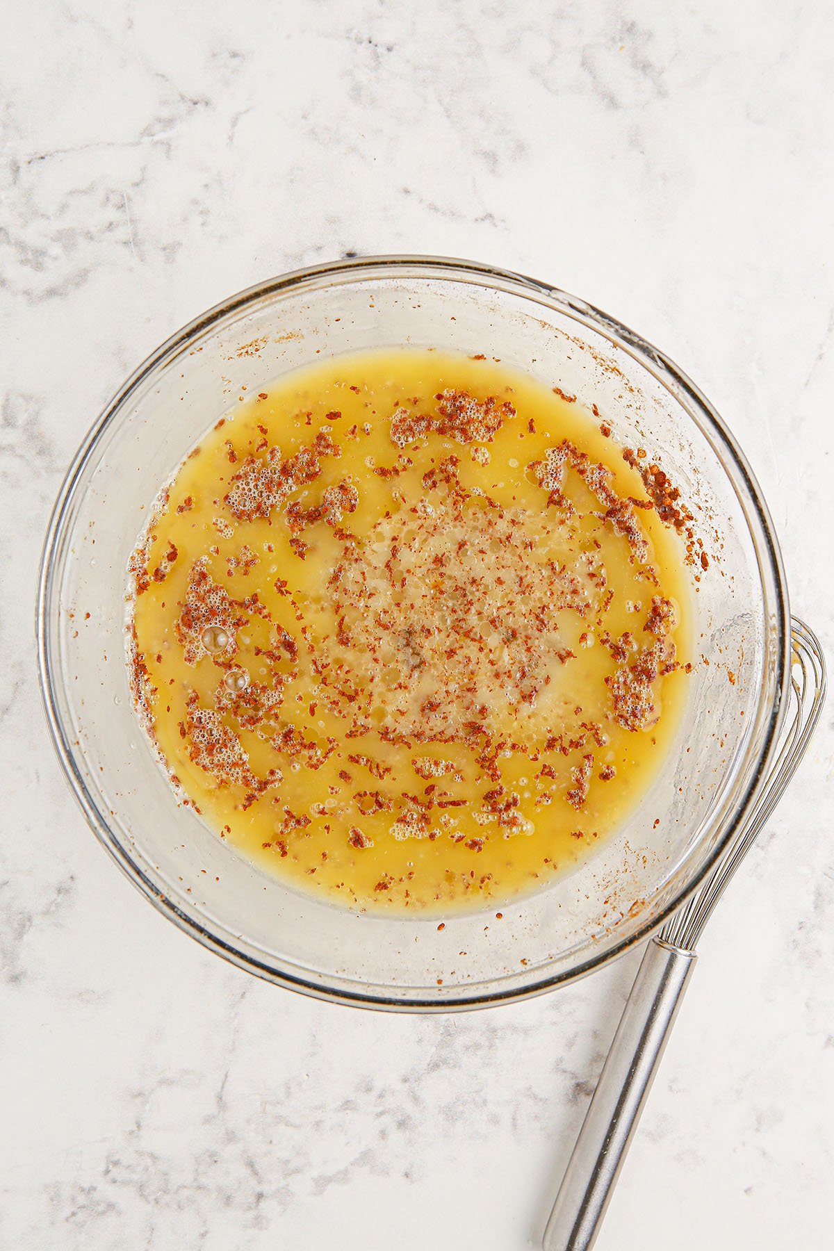 Melted butter, eggs, heavy cream, maple syrup, vanilla extract, and cinnamon in a glass mixing bowl.