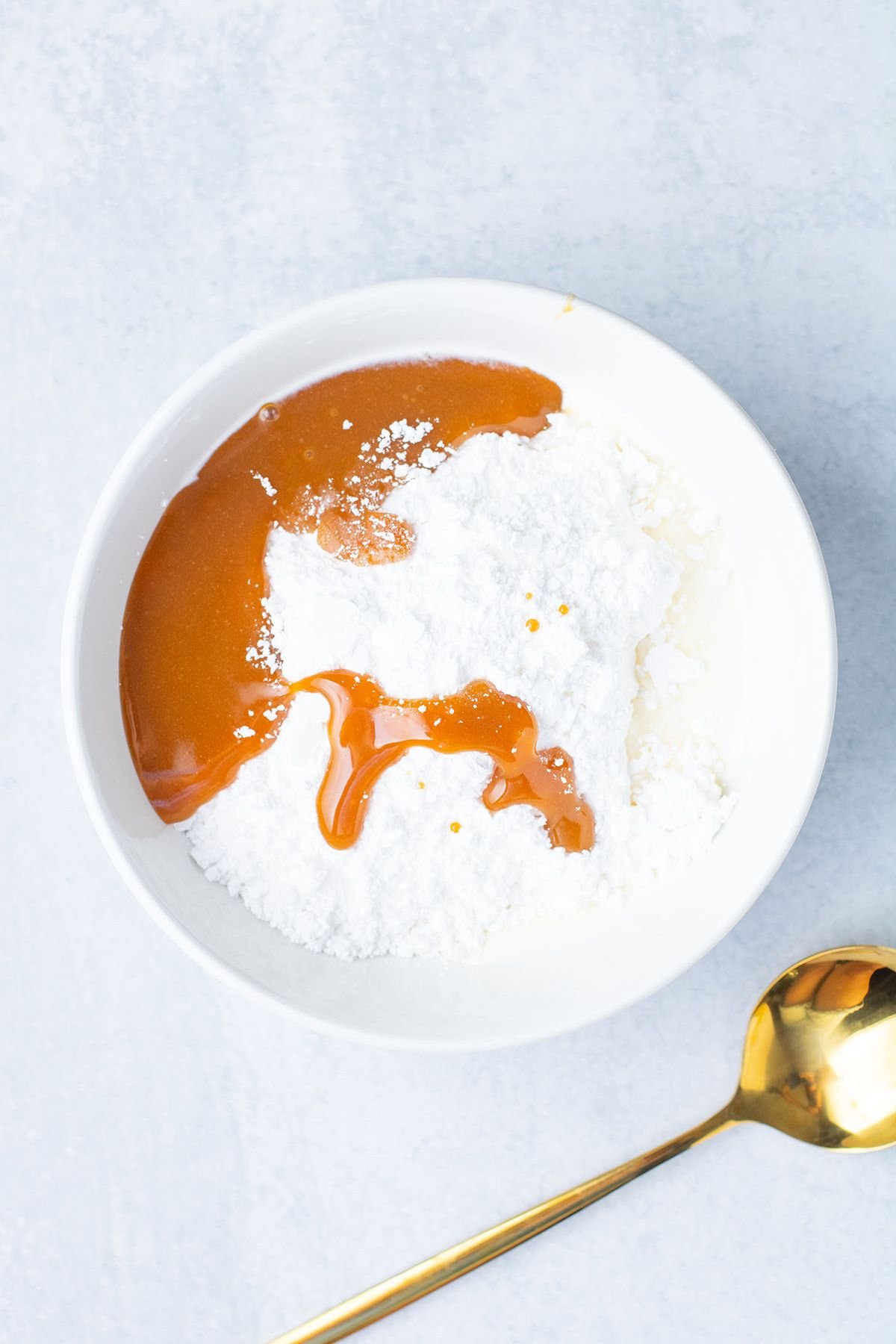 Powdered sugar, caramel sauce, and heavy cream in a white bowl.