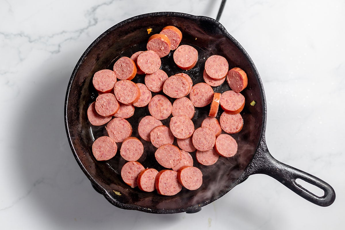 Sliced smoked sausage in a cast iron skillet.