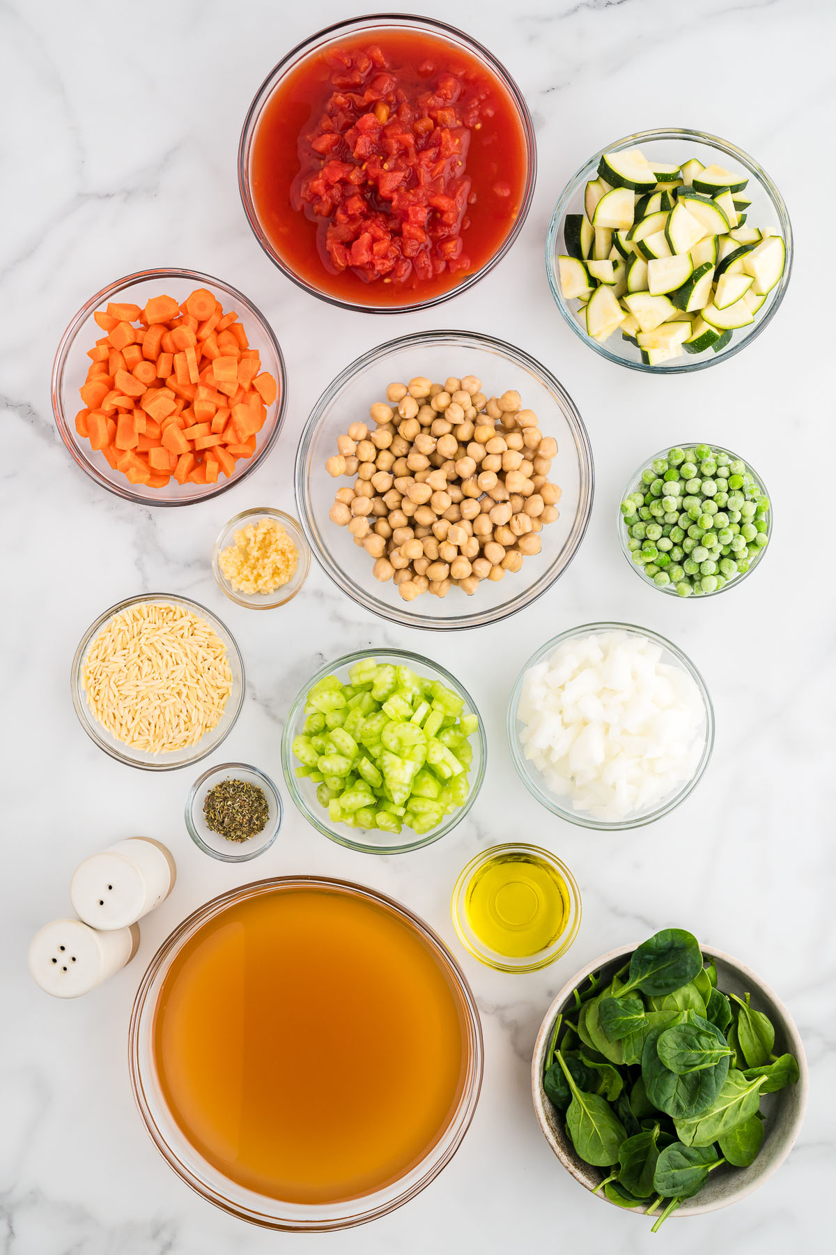 Ingredients to make vegetable orzo soup are set out on the counter.