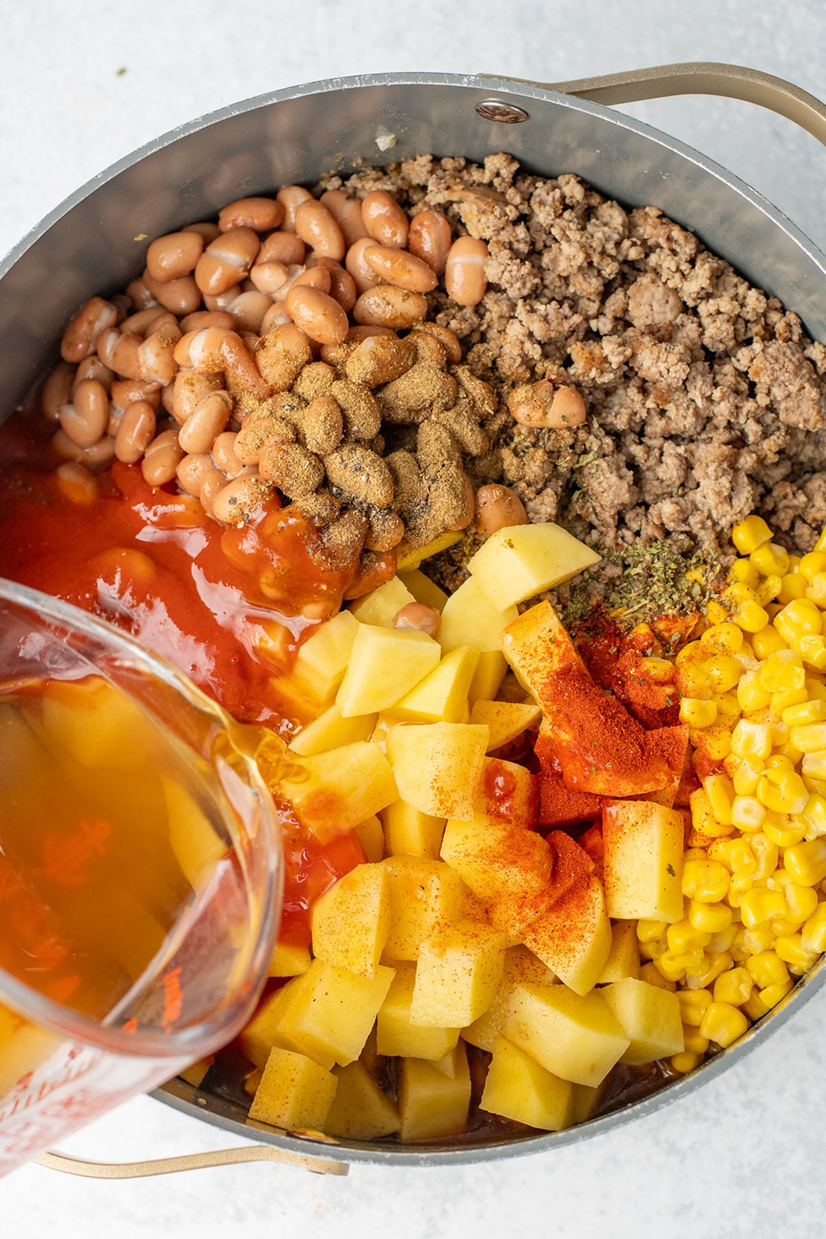 Beef broth added to the ground beef, beans, and vegetables in the large pot.