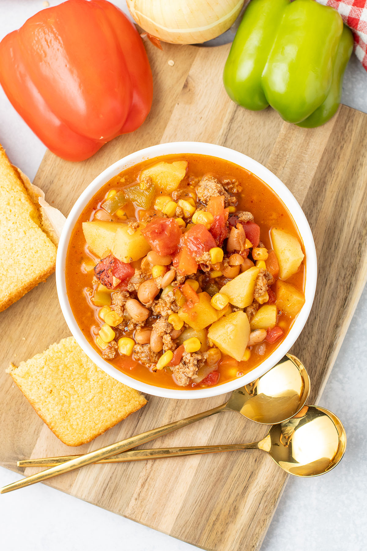 Cowboy Soup in a white bowl with a side of cornbread on a wooden board.