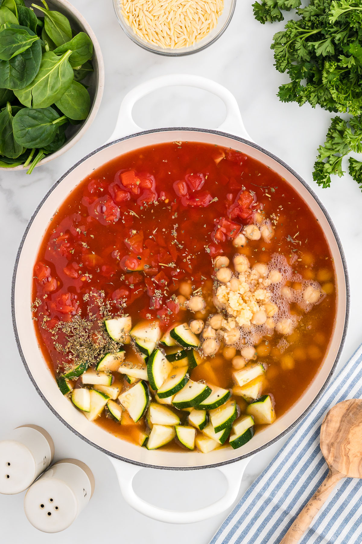 Vegetable broth is added to the vegetables and beans in the large pot.