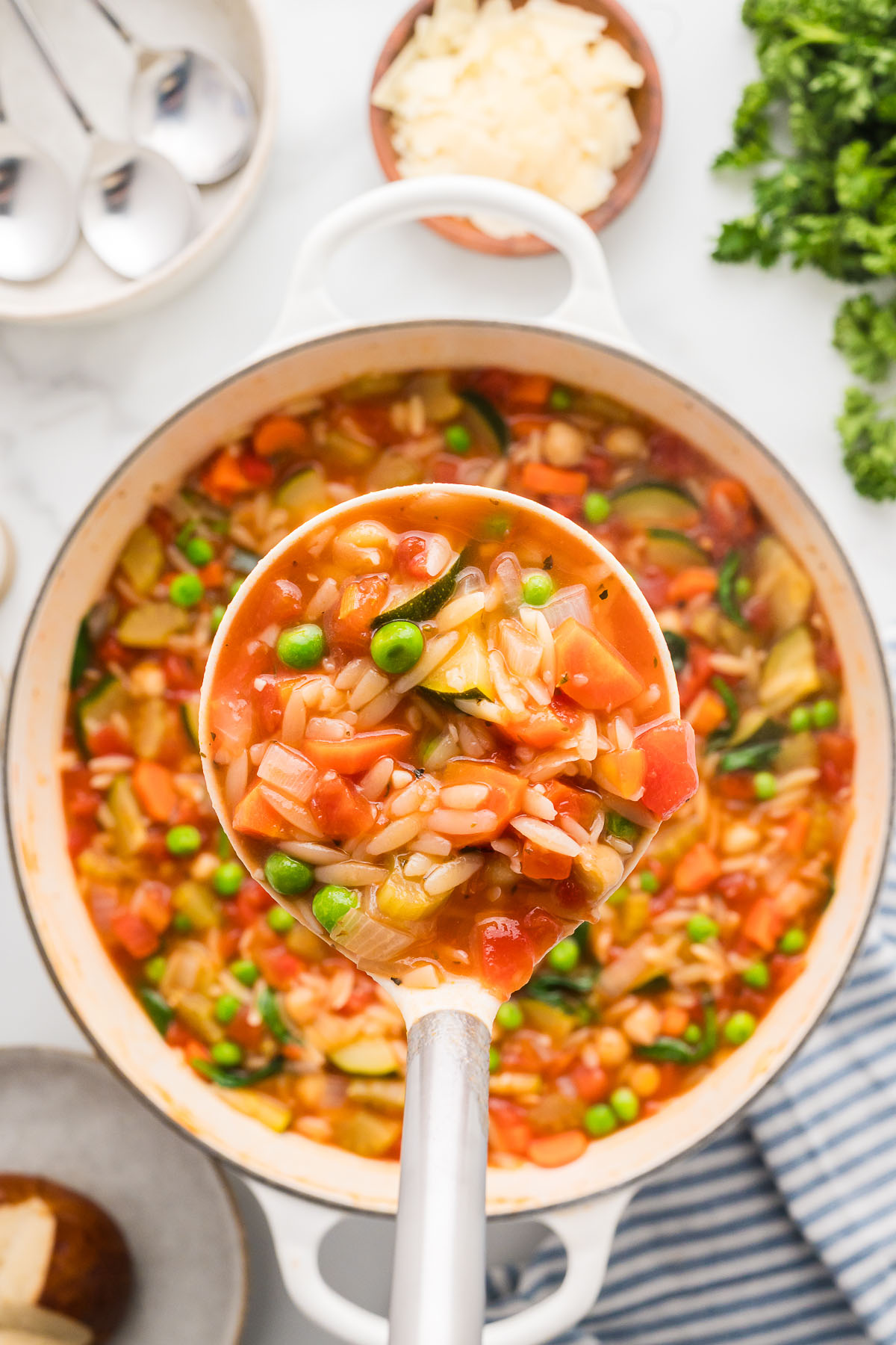 vegetable orzo soup in a large pot, with a serving in a ladle. 