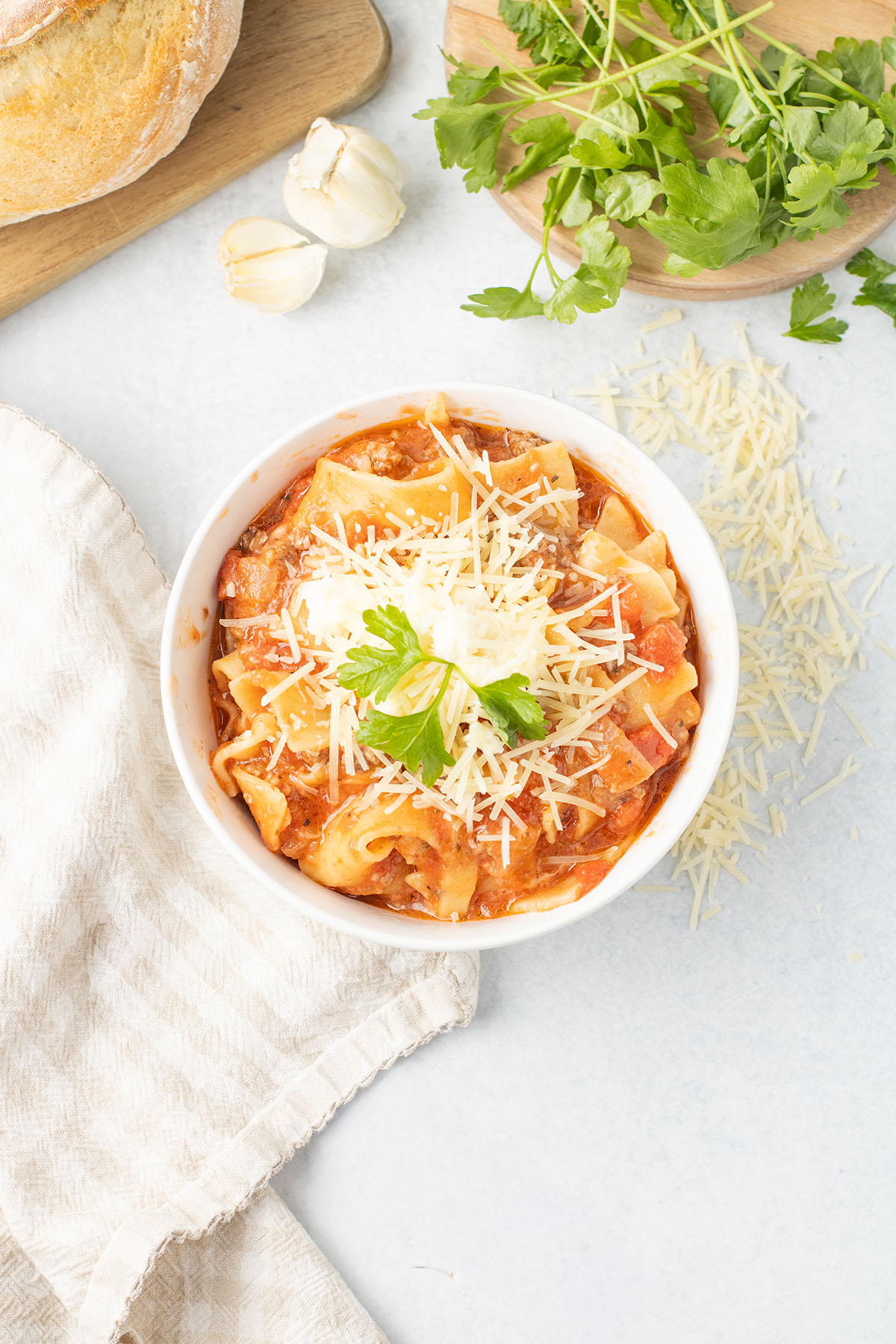 Lasagna Soup topped with Parmesan cheese and Parsley in a white bowl.